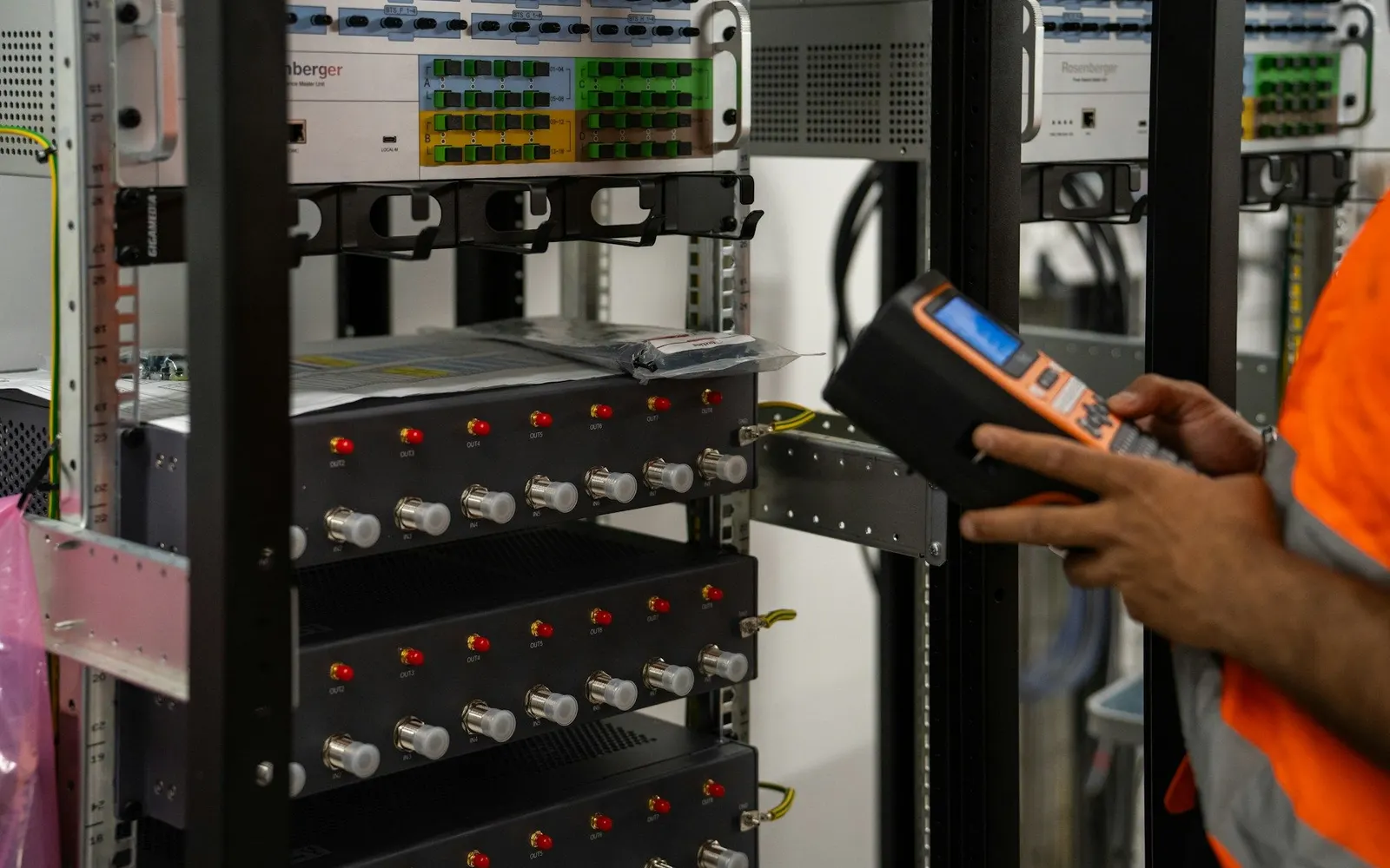 A technician checking server racks in a data centre with a diagnostic tool