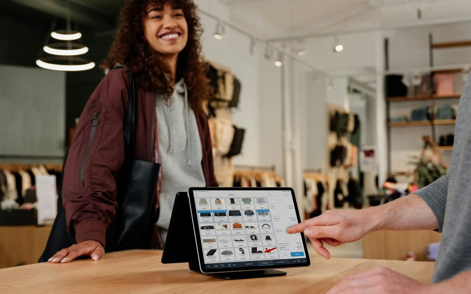A customer at a shop counter using a tablet point-of-sale system