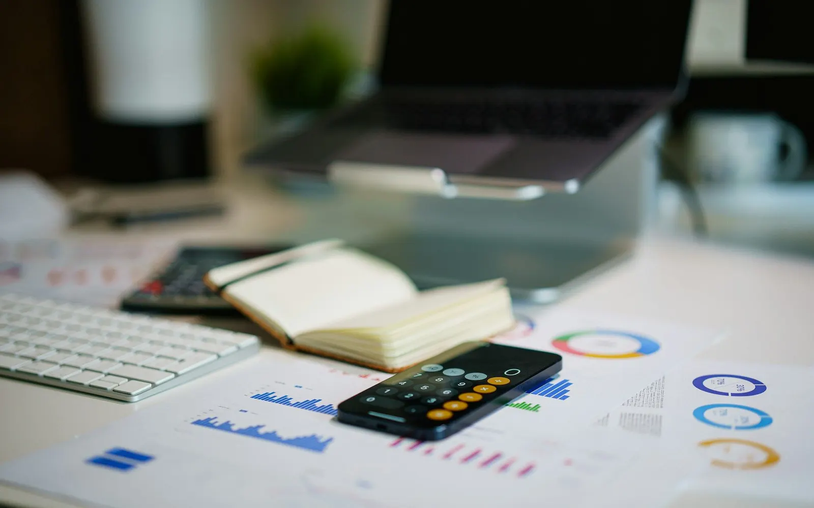 Financial charts, a calculator and a notebook on an office desk