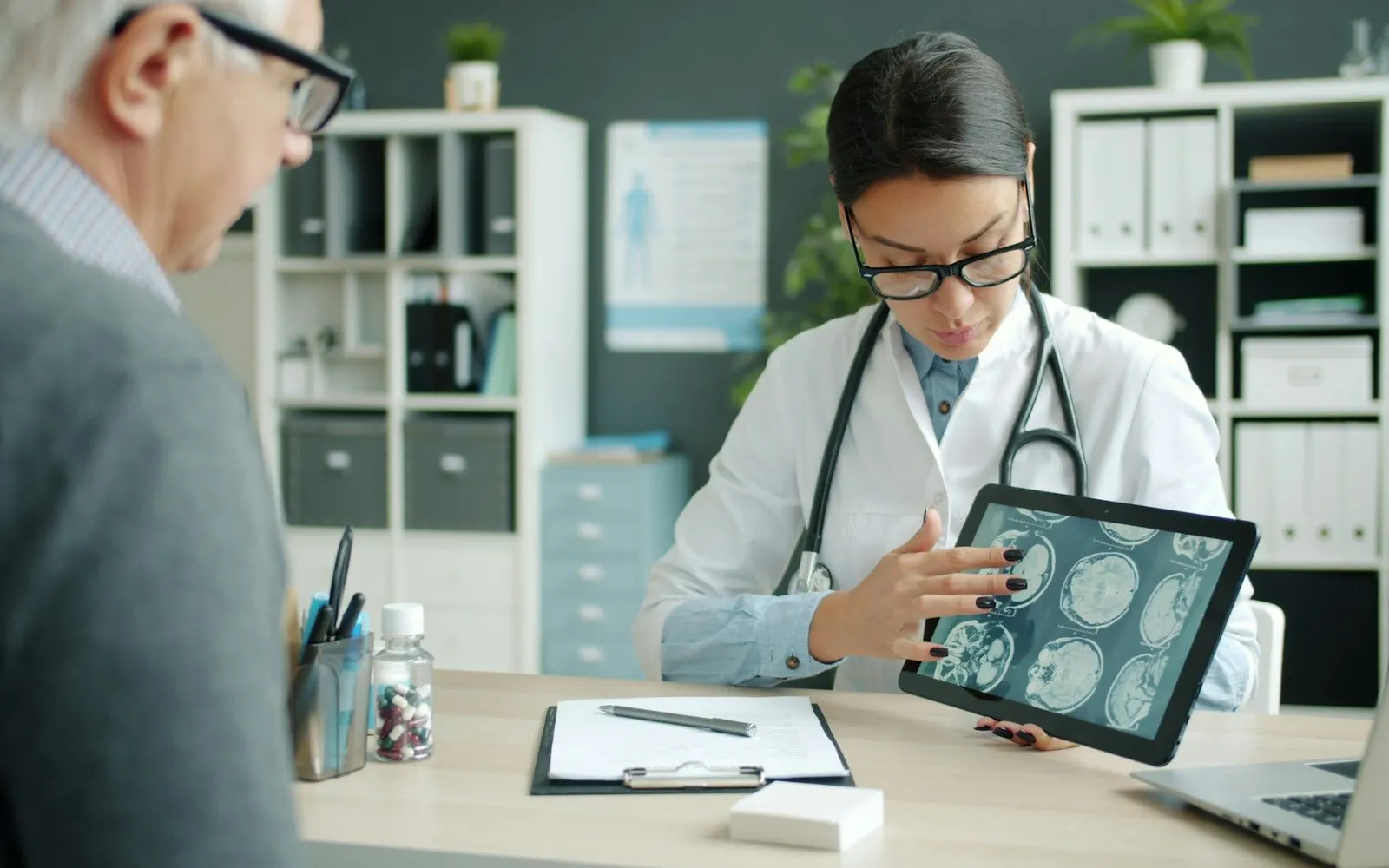 A doctor reviewing brain scans on a tablet with a patient