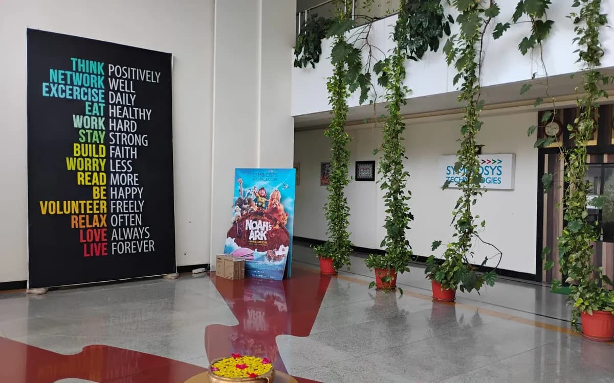 A "Think positively" wall beside a Noah's Ark poster and the Symbiosys Technologies sign