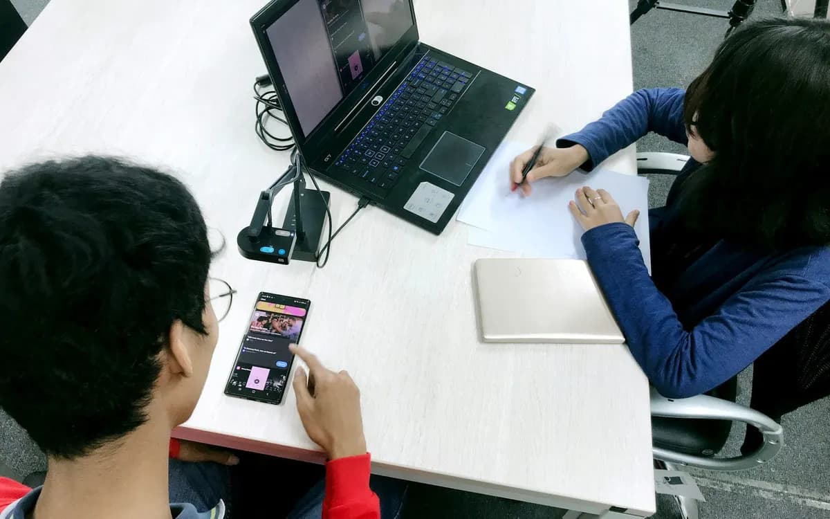 One person testing an app on a phone while a colleague takes notes