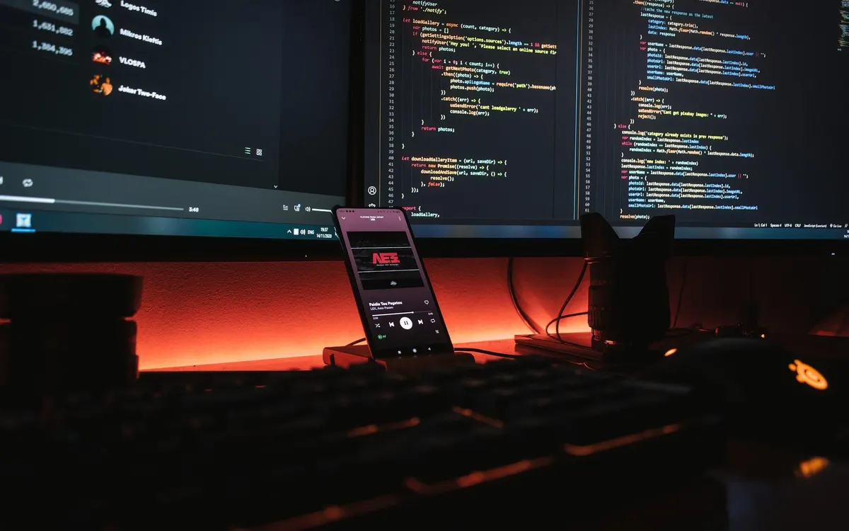 Monitors showing test code beside a phone on a desk