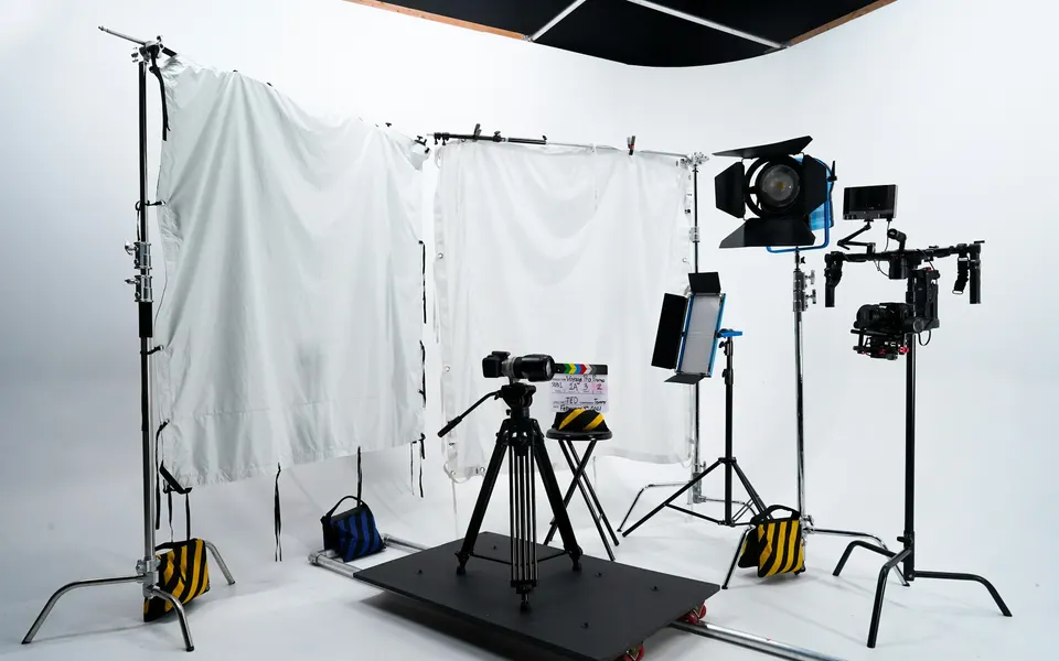 An empty white film studio with lights and cameras
