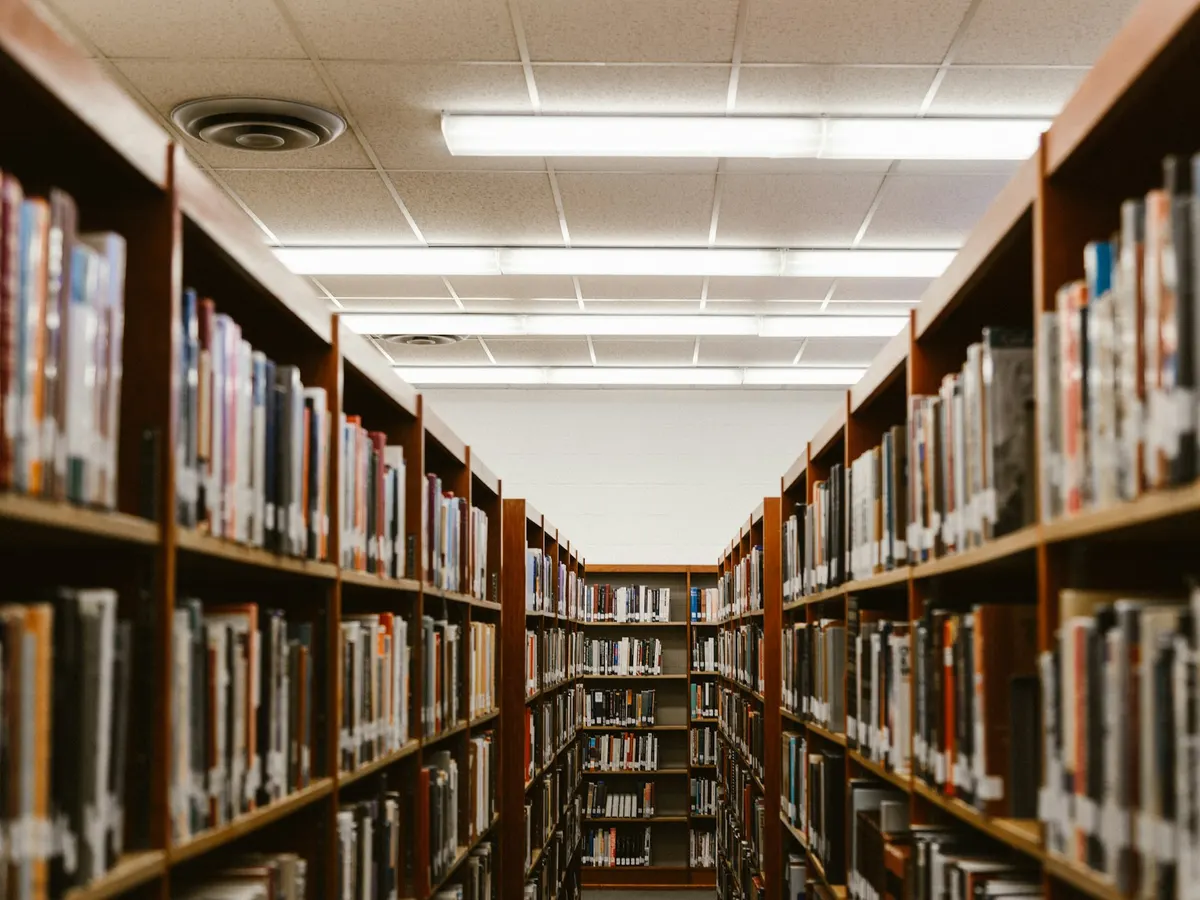 An aisle between tall library shelves full of books