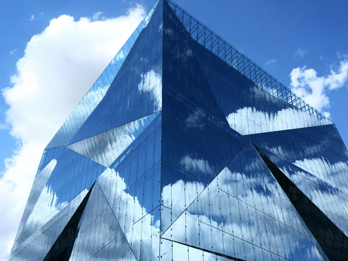 A faceted glass building reflecting the sky