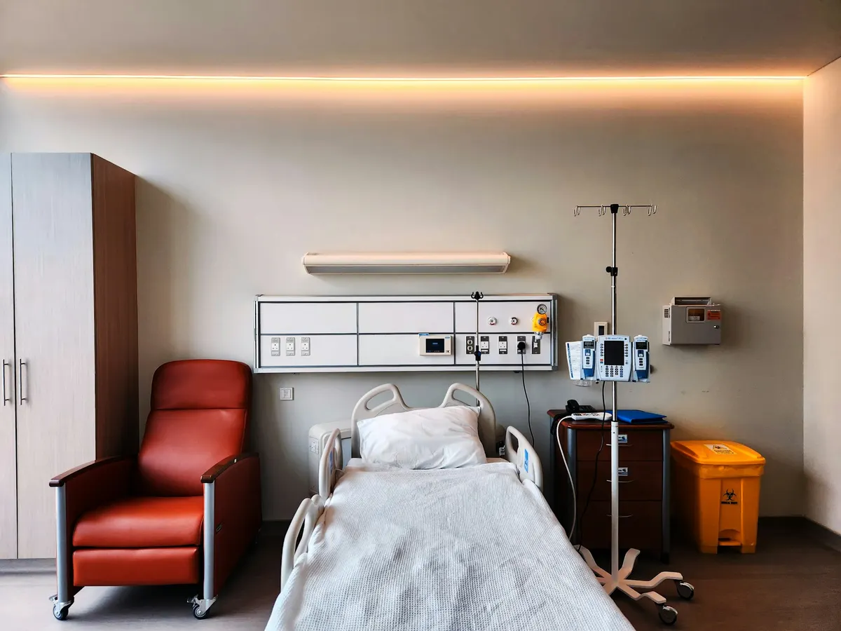 An empty, modern hospital room with a bed, recliner and monitoring equipment