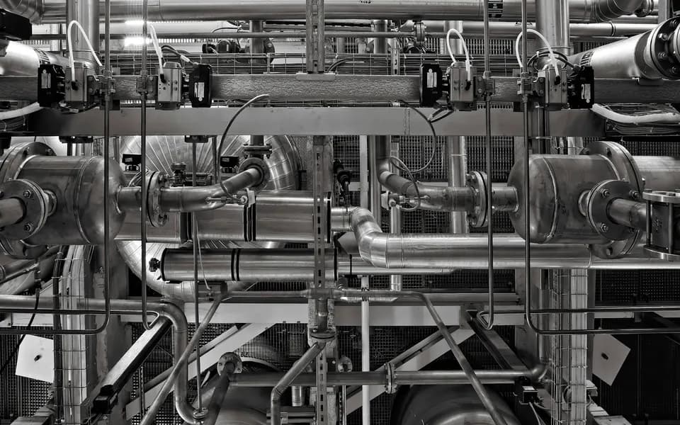 A dense network of steel pipes and valves in a process plant