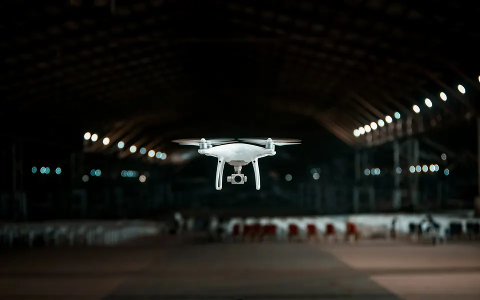 A drone hovering inside a large industrial hangar