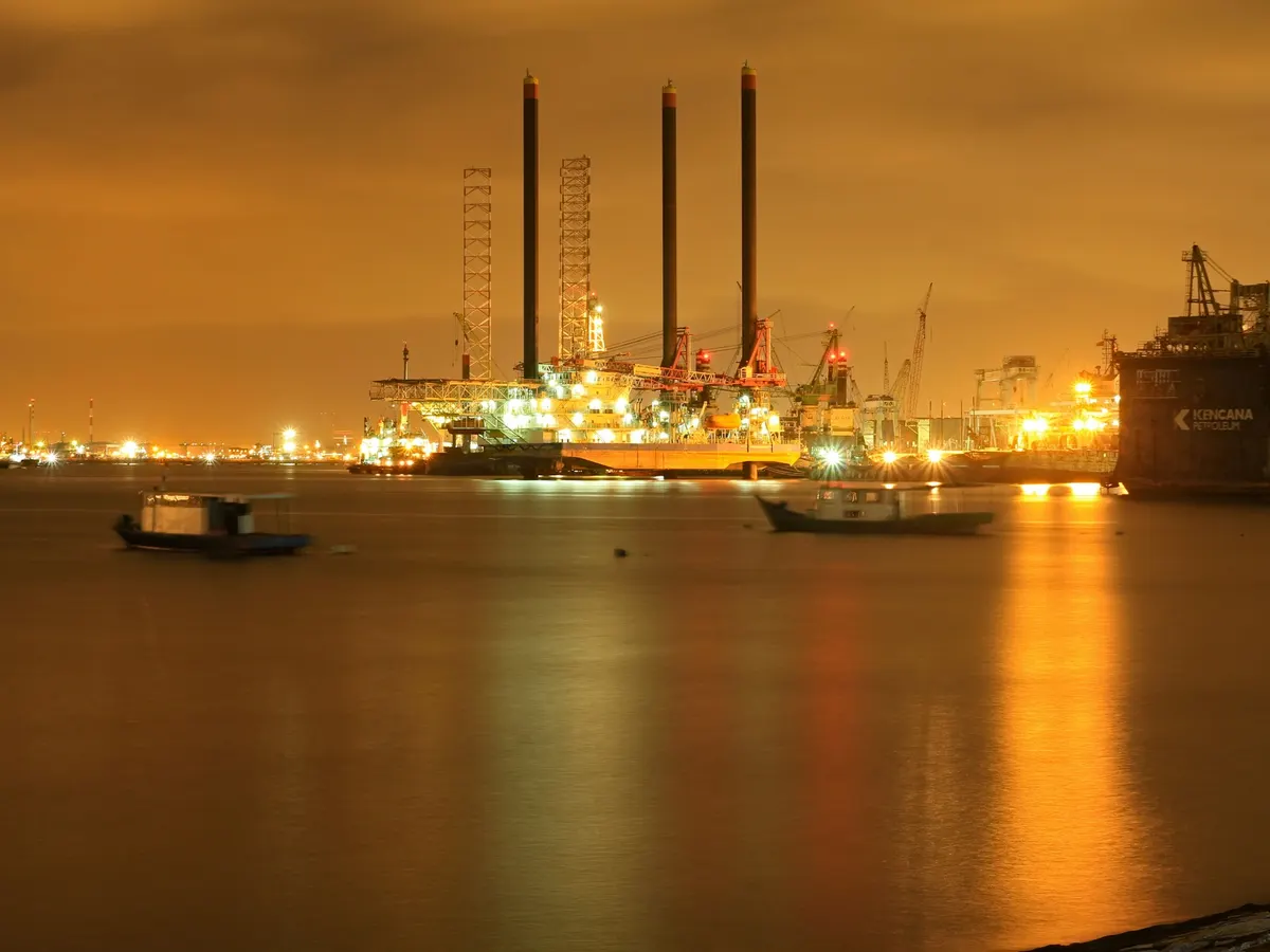 An offshore rig and industrial harbour lit up at night