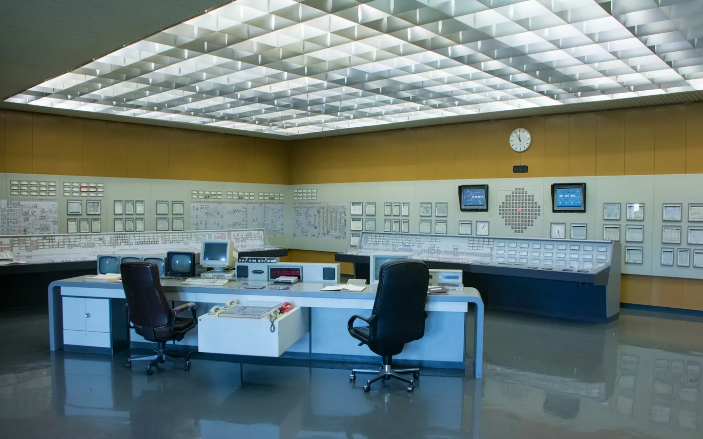 An empty operations control room with consoles and wall panels